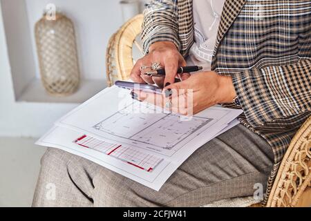Femme décoratrice d'intérieur avec plans d'intérieur pour un nouveau projet contient le téléphone portable Banque D'Images