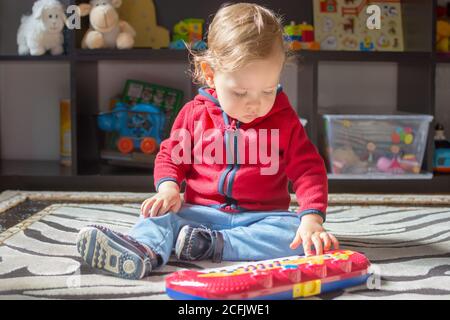 Joyeux bébé garçon sucré ayant du plaisir à jouer avec son clavier piano, à la maison Banque D'Images