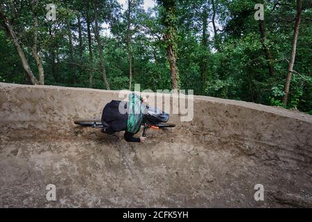 Cycliste masculin en vélo pour faire de la descente le long d'un sentier sablonneux et réaliser des tours extrêmes dans les bois Banque D'Images