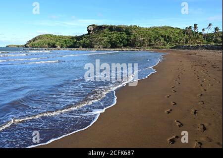 La plage de sable noir de la baie de Talofofo à Guam. Banque D'Images