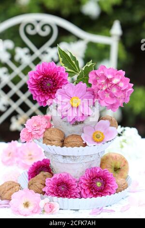 décoration romantique avec fleurs roses d'été, noix et pomme sur le whatnot Banque D'Images