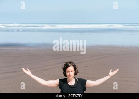 Jeune femme de sport faisant de la méditation tout en pratiquant le yoga sur sable de mer Banque D'Images
