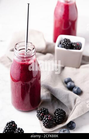 Smoothie frais à base de baies sur bouteilles en verre et paille métallique réutilisable pour la boire. Banque D'Images