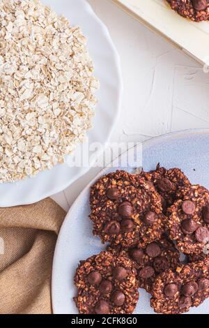 Quelques biscuits aux flocons d'avoine et aux bananes sur une assiette bleue avec flocons d'avoine. Image verticale en hauteur Banque D'Images