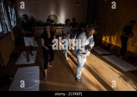 Groupe de personnes avec instructeur effectuant des mouvements fluides avec étiré les bras pendant le chi kung pratique en studio Banque D'Images