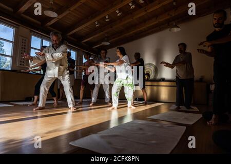 Groupe de personnes avec instructeur effectuant des mouvements fluides avec étiré les bras pendant le chi kung pratique en studio Banque D'Images