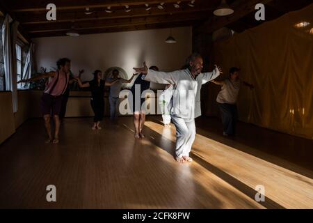 Groupe de personnes avec instructeur effectuant des mouvements fluides avec étiré les bras pendant le chi kung pratique en studio Banque D'Images