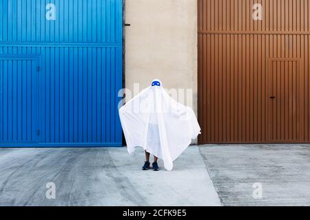 enfant sans visage en costume fantôme blanc effrayant avec les bras étirés En ville pendant Halloween Banque D'Images