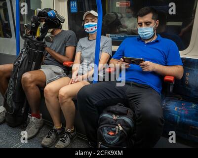 Les passagers du train souterrain de Londres portent un masque et tentent de pratiquer la distanciation sociale. Banque D'Images