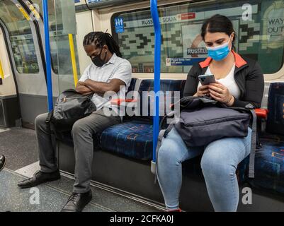 Les passagers du train souterrain de Londres portent un masque et tentent de pratiquer la distanciation sociale. Banque D'Images