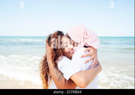 Vue latérale du contenu afro-américain adulte mère et jeune fille debout sur la plage près de la mer Banque D'Images