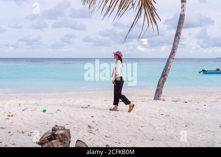 Vue latérale complète sur les jeunes femmes asiatiques qui marchent sur la plage tropicale avec sable blanc et eau de mer bleue Tout en passant des vacances d'été sur l'île de Bodufolhudhoo aux Maldives Banque D'Images