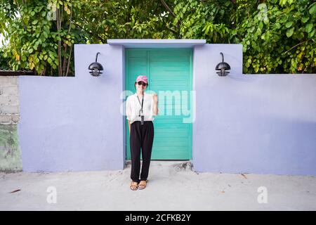 Pleine corps heureux jeune asiatique femme touriste debout près de coloré Porte et main de la main tout en passant des vacances d'été aux Maldives îles Banque D'Images