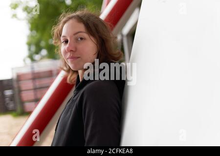 Faible angle de la femme calme surfeuse sur un remblai en bois avec planche à aubes tout en se relaxant après l'entraînement et regarder appareil photo Banque D'Images