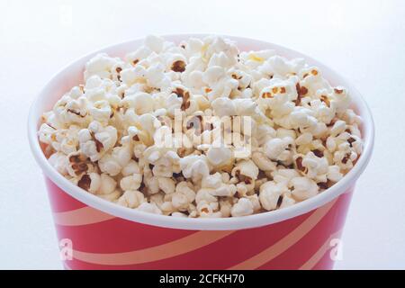 Pop-corn dans un seau en carton à rayures rouges isolé sur fond blanc Banque D'Images