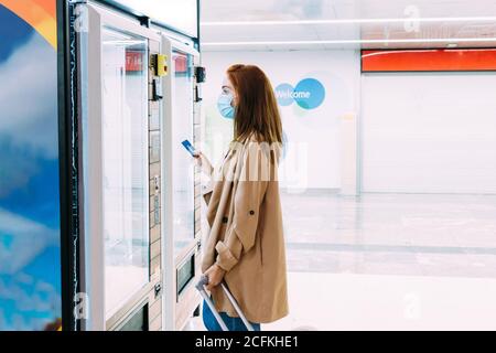 femme avec un masque de visage utilise sa carte de crédit à payez au distributeur automatique Banque D'Images