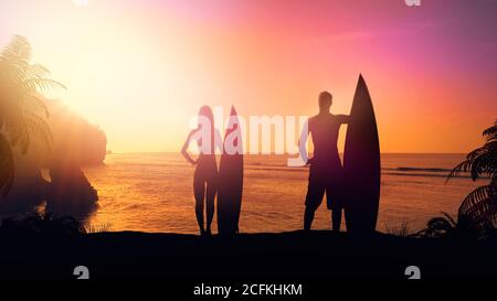 Surfeurs sur la plage contre un coucher de soleil lumineux. Banque D'Images