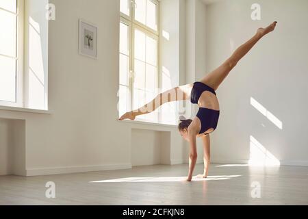 Svelte dans le sport brassière haut et short faisant la main tout en pratiquant la gymnastique en studio Banque D'Images