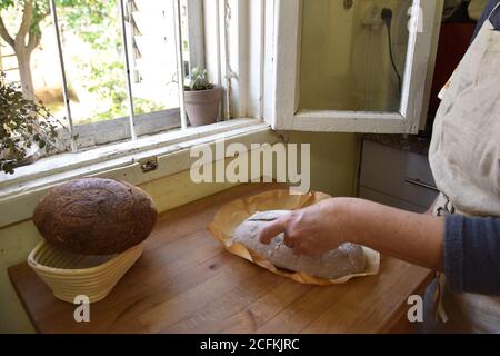 Une femme cuit un pain frais et croustillant de pain fait maison. Pain aigre rustique fait maison sur une planche à découper en bois. Tranche de pain brun. Tranches de pain. Photo de haute qualité Banque D'Images