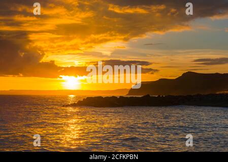 West Bay Dorset, Royaume-Uni. 6 septembre 2020. Météo Royaume-Uni. Les nuages brillent une orange dorée au coucher du soleil après une douche épaisse à la station balnéaire de West Bay à Dorset. Crédit photo : Graham Hunt/Alamy Live News Banque D'Images