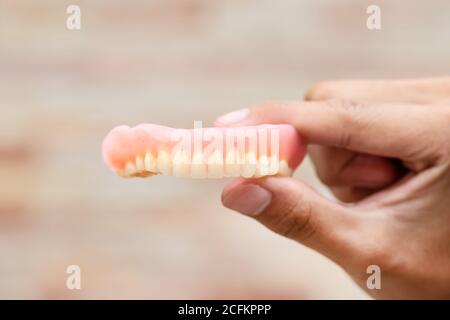 Un homme tient des prothèses dentaires entre ses mains. Dentiers amovibles flexibles. Fausses dents. Banque D'Images