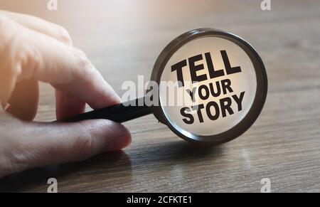 Racontez votre histoire sous la loupe à la main sur une table en bois. Concept d'affaires Banque D'Images
