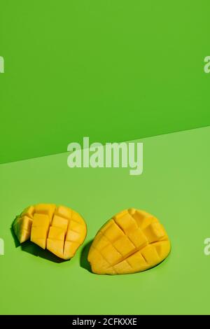 De dessus de gros plan de mangue fraîche mûre juteuse à moitié coupée en tranches en morceaux sur fond vert vif Banque D'Images