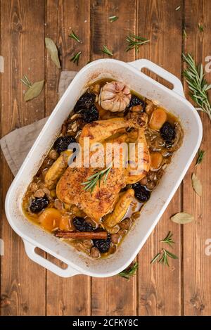 Vue de dessus du poulet farci cuit dans un plat à l'ail et un bâton de cannelle placé sur une table en bois Banque D'Images