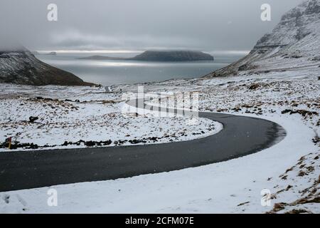 Route de campagne vide et sinueuse traversant le terrain enneigé du désert Froid jour d'hiver avec ciel bleu en Islande Banque D'Images