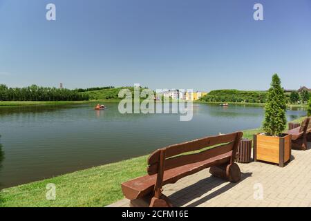 Village allemand, Krasnodar, Russie-juin 09, 2019: Bancs près de l'étang dans un quartier urbain confortable. Les gens se font monter sur les catamarans. Sortie Banque D'Images