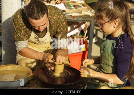 Moldavanskoye, Krymsk, Russie-05 octobre 2019: Un potier enseigne à une fille comment faire une carafe d'argile sur une roue de Potters. Master class au festival de youn Banque D'Images