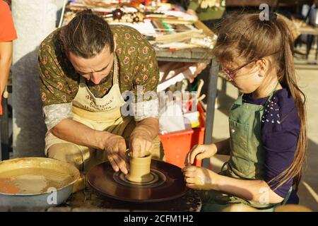 Moldavanskoye, Krymsk, Russie-05 octobre 2019 : un potier enseigne à une fille comment faire une carafe d'argile jaune. Roue de potters en rotation. Classe maître à la f Banque D'Images