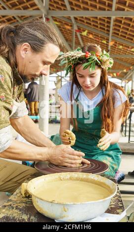 Moldavian, Krymsk, Russie-05 octobre 2019: Le Maître montre à la jeune fille dans une couronne de fleurs comment faire un pichet d'argile. Master class à la festiva Banque D'Images