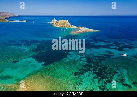 Vue aérienne des bateaux dans un océan bleu clair cristal à côté d'une petite île (Kolokitha, Crète, Grèce) Banque D'Images