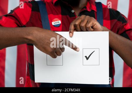 Jeune mécanicien contemporain pointant sur la tique dans l'une des cases sur bulletin de vote Banque D'Images