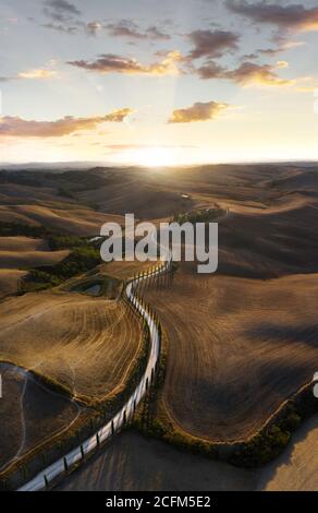 Coucher de soleil sur la belle route courbe S qui traverse Val d'Orcia en Toscane, Italie Banque D'Images