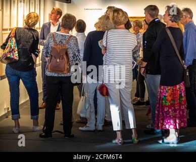 Un groupe de visiteurs se tient debout rapprochés devant la section d’exposition « Liebesgeschichten » (« Histoires d’amour ») de l’exposition « Explique-moi, l’amour ! » (8 juillet–14 octobre 2018) au musée Clemens Sels, avec Ulf Sölter, alors directeur adjoint du musée, visible à gauche en conversation avec un visiteur, à Neuss, en Allemagne. Banque D'Images