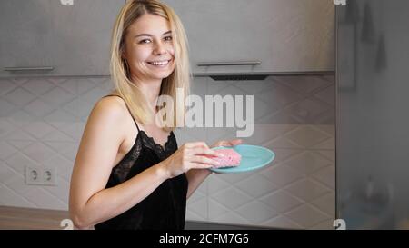 Une jeune femme lave les plats dans une cuisine moderne Banque D'Images