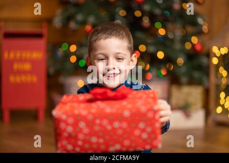 Noël fabuleux, petit garçon tenant une grande boîte rouge avec un cadeau de Santa. Banque D'Images