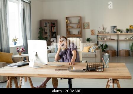 Mûr blonde gaie femme riant devant l'écran d'ordinateur à la maison Banque D'Images