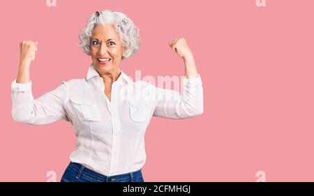 Femme sénior aux cheveux gris vêtue de vêtements décontractés montrant les bras muscles souriant fier. Concept de forme physique. Banque D'Images