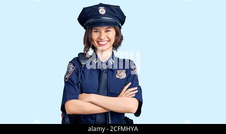 Jeune belle fille portant l'uniforme de police visage heureux souriant avec des bras croisés regardant la caméra. Personne positive. Banque D'Images