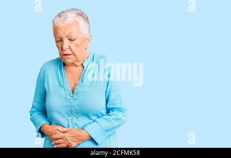 Senior belle femme avec les yeux bleus et les cheveux gris portant robe d'été avec la main sur l'estomac parce que l'indigestion, la maladie douloureuse sentiment malaise. ach Banque D'Images