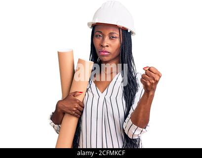 Une jeune femme afro-américaine portant un chapeau d'architecte tenant des plans de rue agacés et frustrés criant avec colère, hurlant fou avec colère et han Banque D'Images