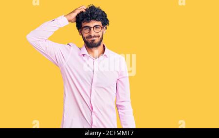 Beau jeune homme aux cheveux bouclés et ours portant des vêtements de travail, embrouiller et se poser des questions. Incertain avec doute, pensant à lui Banque D'Images