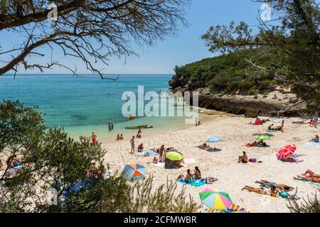 Belle vue sur la plage avec des touristes et des parasols lors d'une journée ensoleillée près de Setubal, Lisbonne, Portugal Banque D'Images