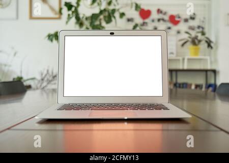 Maquette d'un ordinateur portable blanc sur une table à la maison, dans un espace de bureau ou dans un café. Banque D'Images