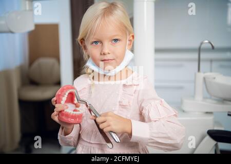 Une petite fille douce jouant un dentiste dans la clinique. Banque D'Images