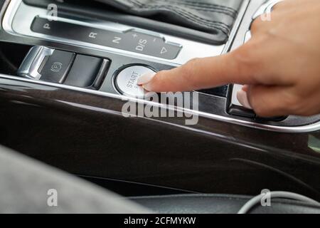 Gros plan de la femme en appuyant sur le bouton de démarrage du moteur de voiture Banque D'Images