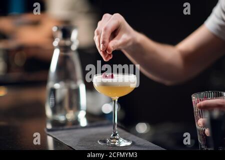 Gros plan d'un verre avec un délicieux cocktail sur la table dans un restaurant. Le barman crée une boisson alcoolisée pour les femmes. Banque D'Images